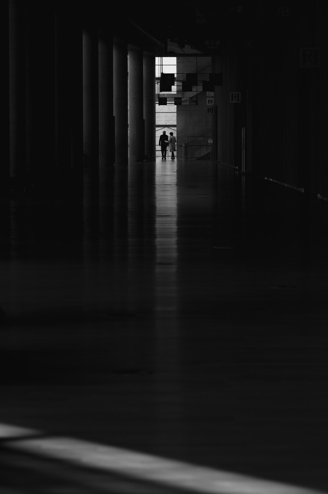 Anonymous silhouette of a person walking away through a long museum corridor